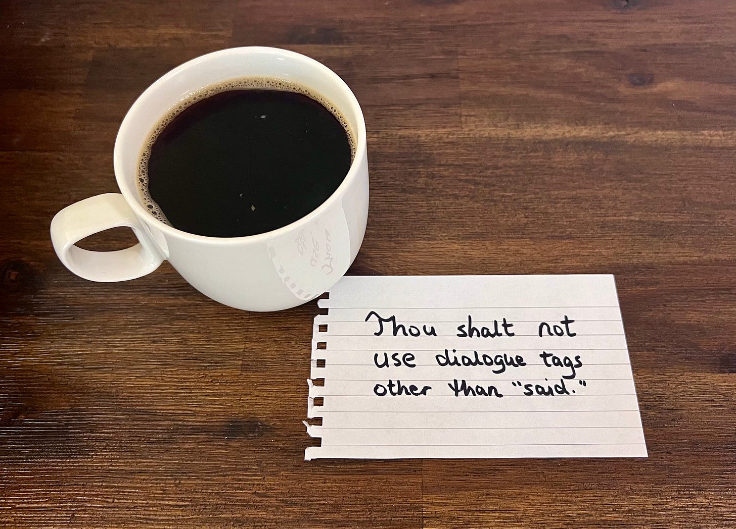 cup of black coffee and a piece of paper with the word, "Thou shalt not use dialogue tags other than 'said.'"