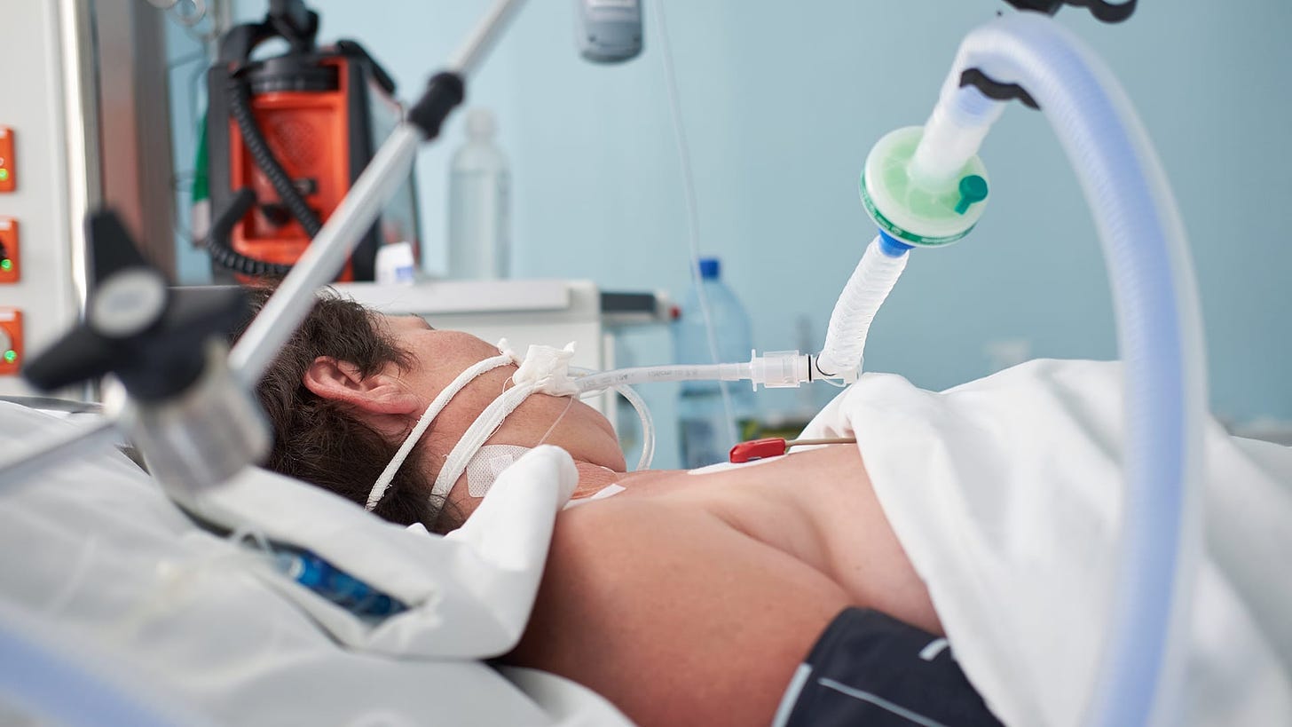 Paramedics wearing protective masks attend to an ill woman in the intensive care unit