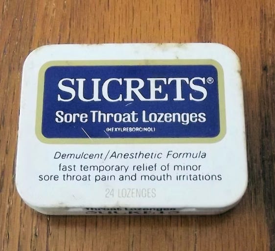 white tin box with the word SUCRETS sore throat lozenges