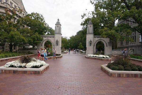 A section of the Indiana University campus featuring arches and a walkway of red brick pavers.