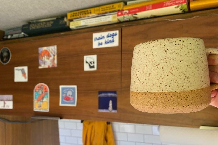 I hold my favorite mug up against our sticker cabinet in our converted camper van