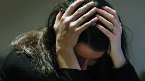 PA Media Woman holding her head in her hands