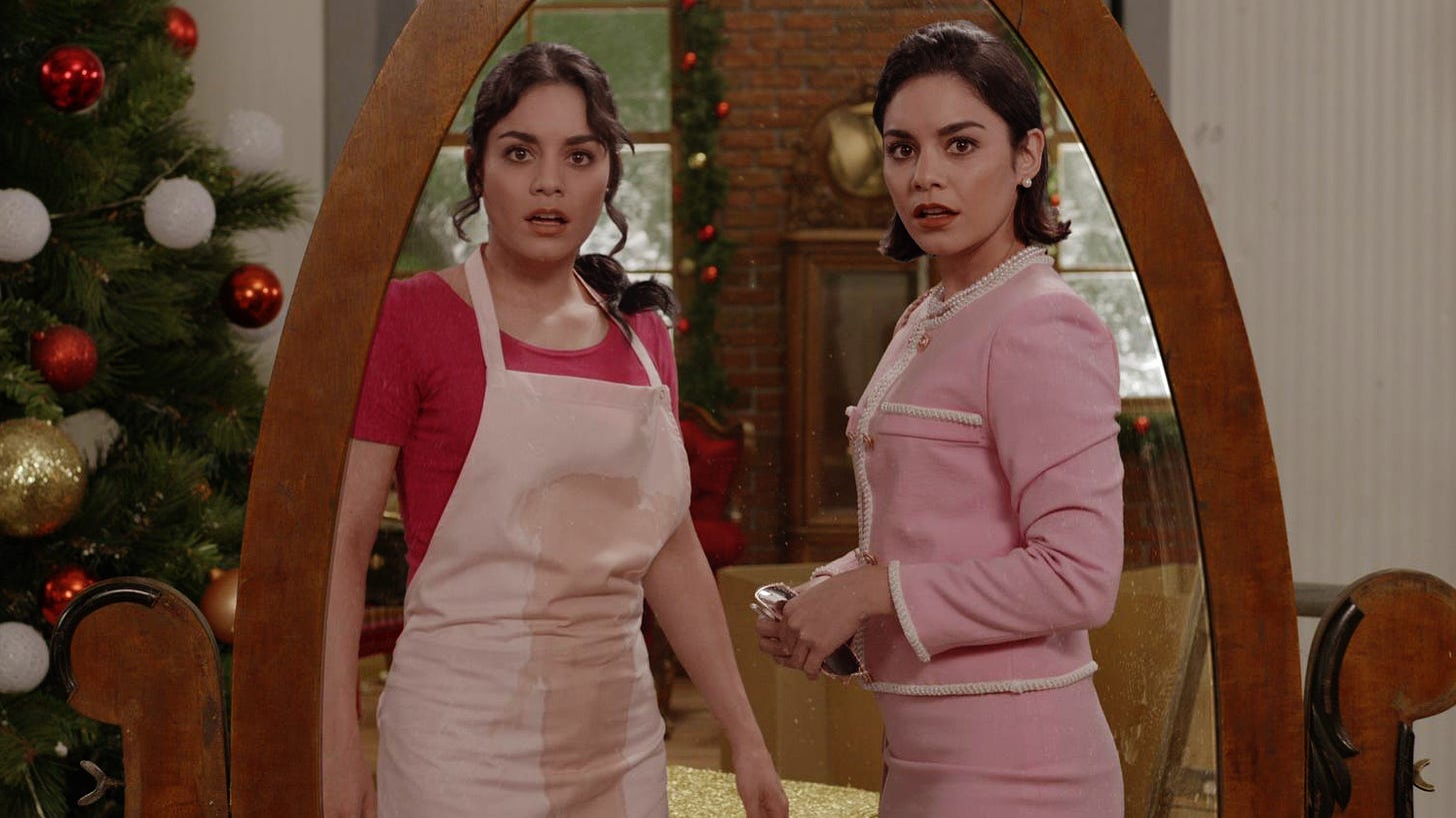 Movie still from The Princess Switch. Identical Vanessa Hudgens characters look in a mirror, one wearing a stained apron and the other dressed rich and fancy. A Christmas tree is in the background.
