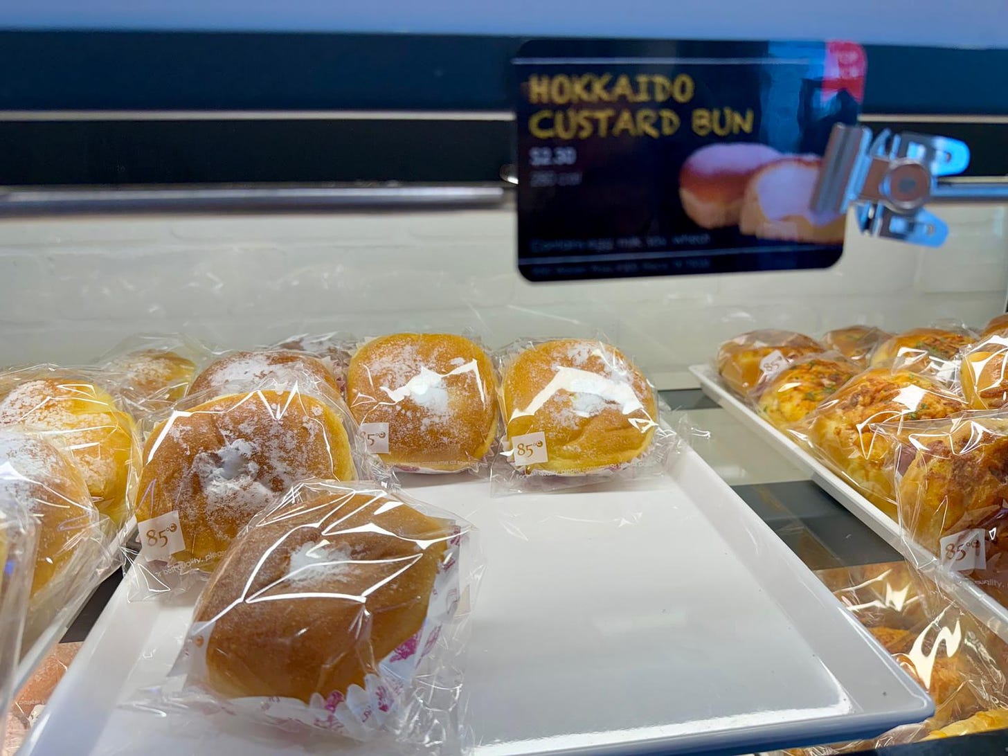 A tray of plastic-wrapped Hokkaido custard buns below a sign that says "Hokkaido custard bun."