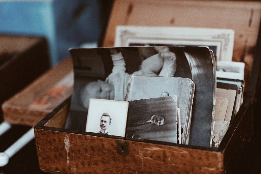 A picture featuring a wooden box full of old black and white photographs of family members