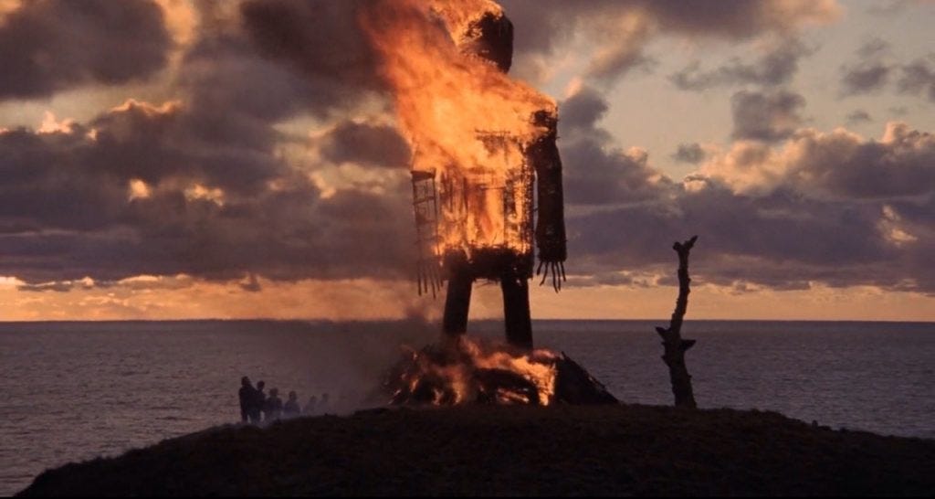image of a giant burning wicker man against a dramatic sky. this is the final scene in thre 1973 folk-horror film, The Wicker Man