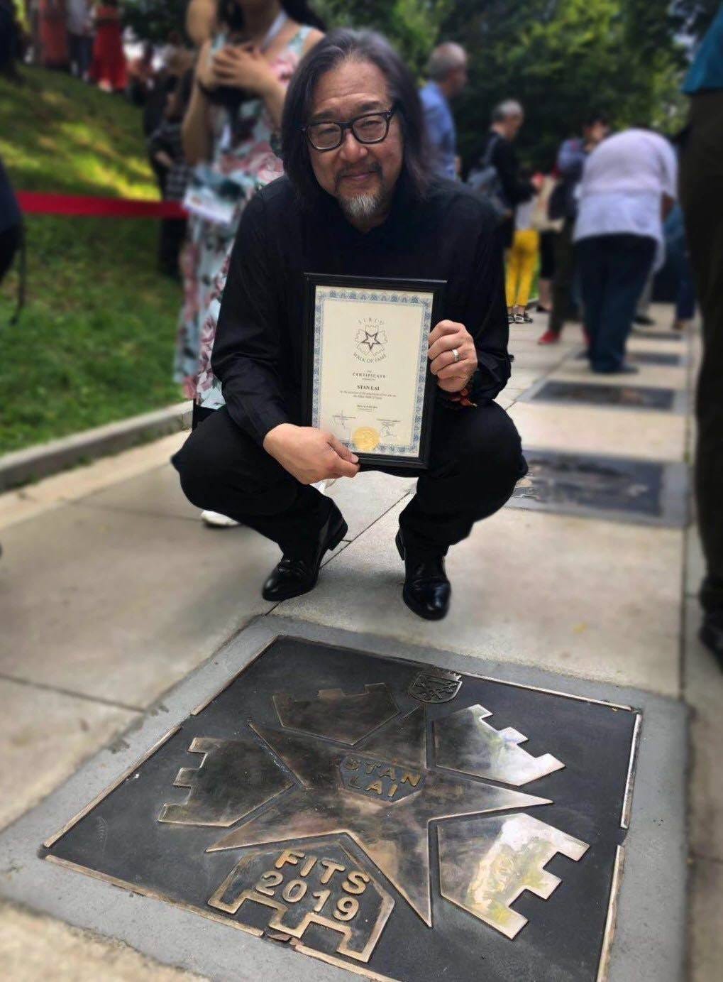 Taiwanese director Stan Lai 賴聲川 kneels beside his star on the Celebrity Walk at the Sibiu International Theatre Festival