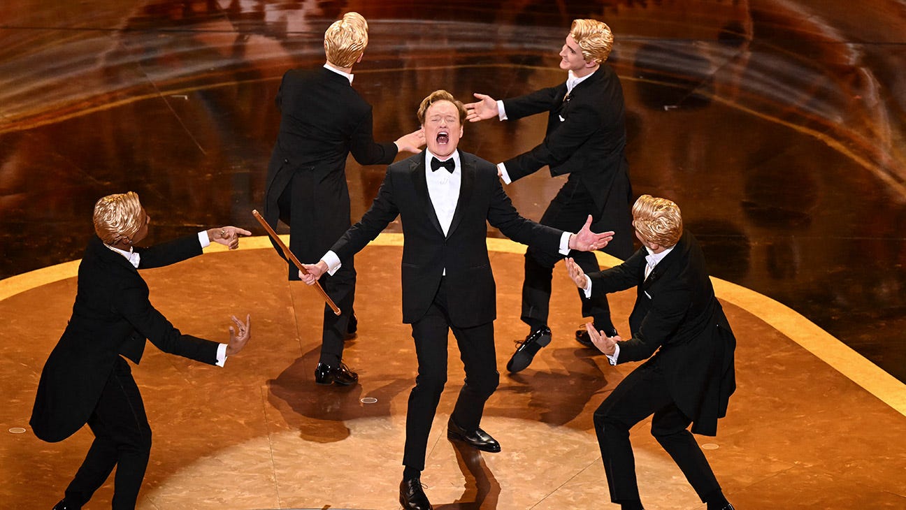 Conan O'Brien, host of the 2025 Oscars ceremony sings in a dinner suit alongside dancers