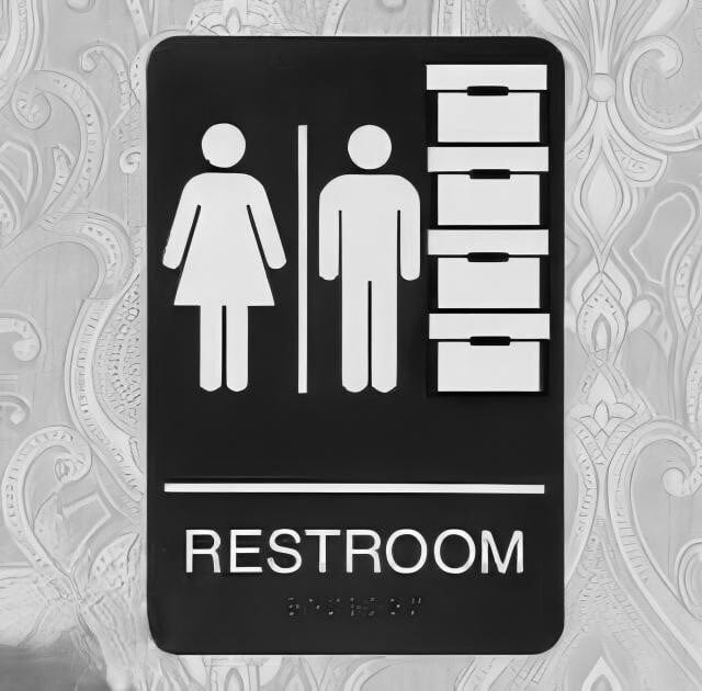 A sign on the door of a restroom depicting symbols for men, women, and boxes of classified documents.