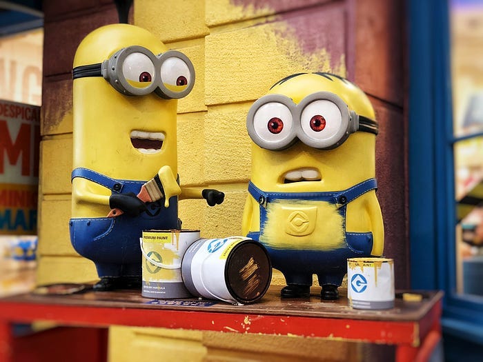 two minions painting a wall yellow