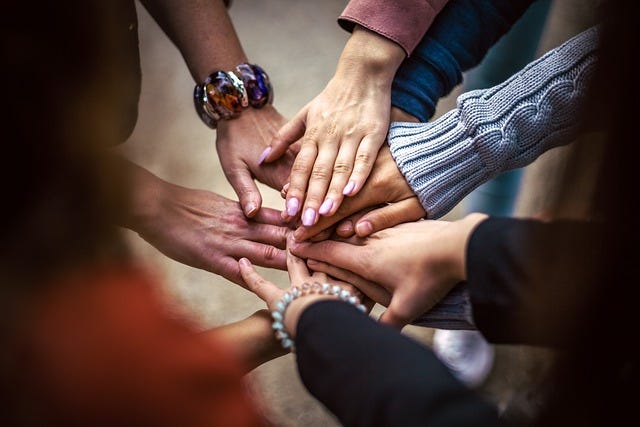 Many hands touching in the middle, demonstrating teamwork and trust