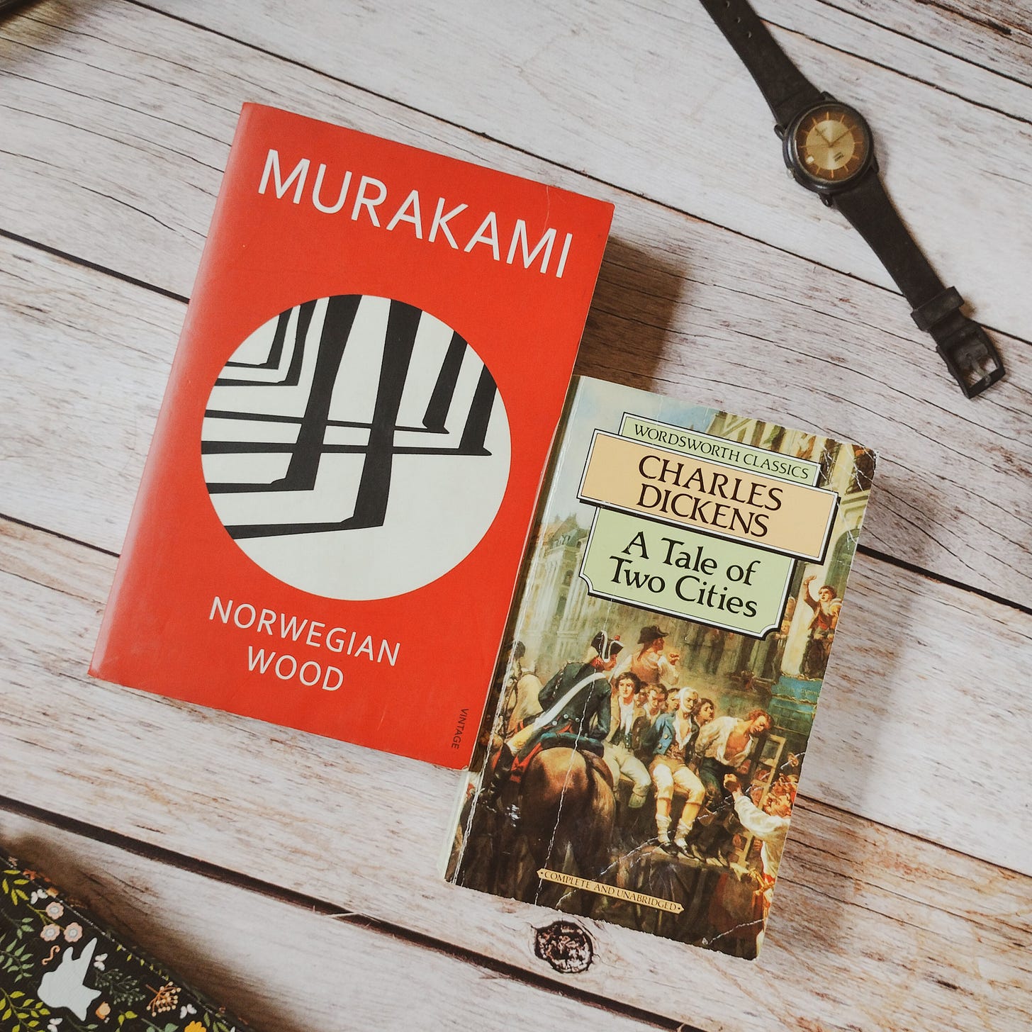 Norwegian Wood by Haruki Murakami and A Tale Of Two Cities by Charles Dickens, on a wooden tabletop