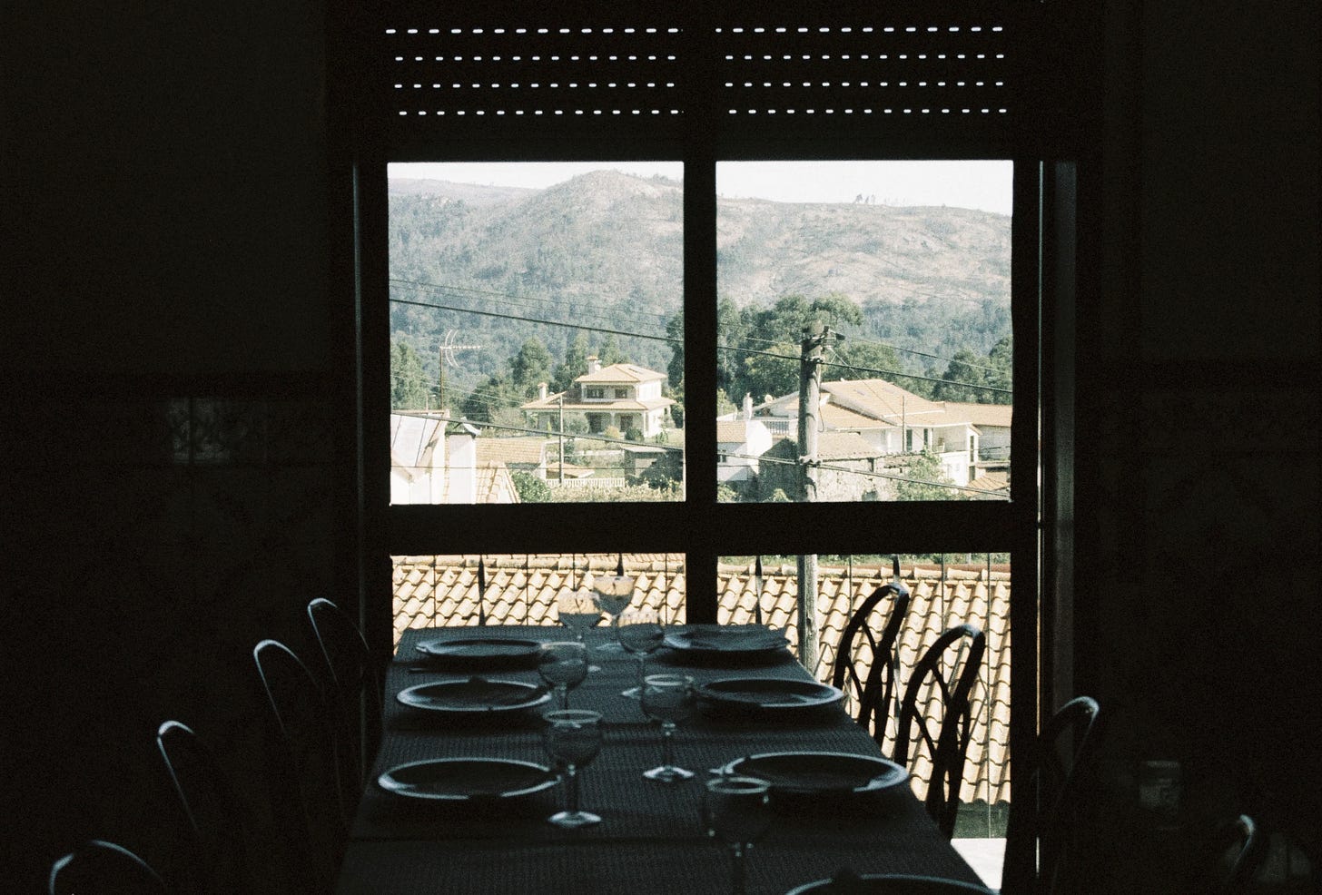 A table set with plates and glasses by a window, overlooking the valley in the cozinha.
