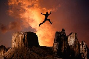 A man leaping from one mountain to another