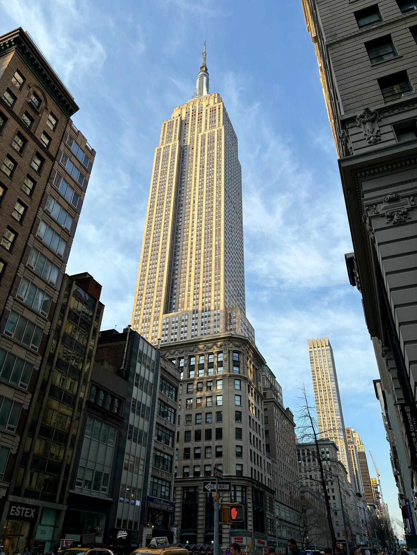 The Empire State Building aglow in the afternoon sun against a blue sky with only wisps of white clouds.