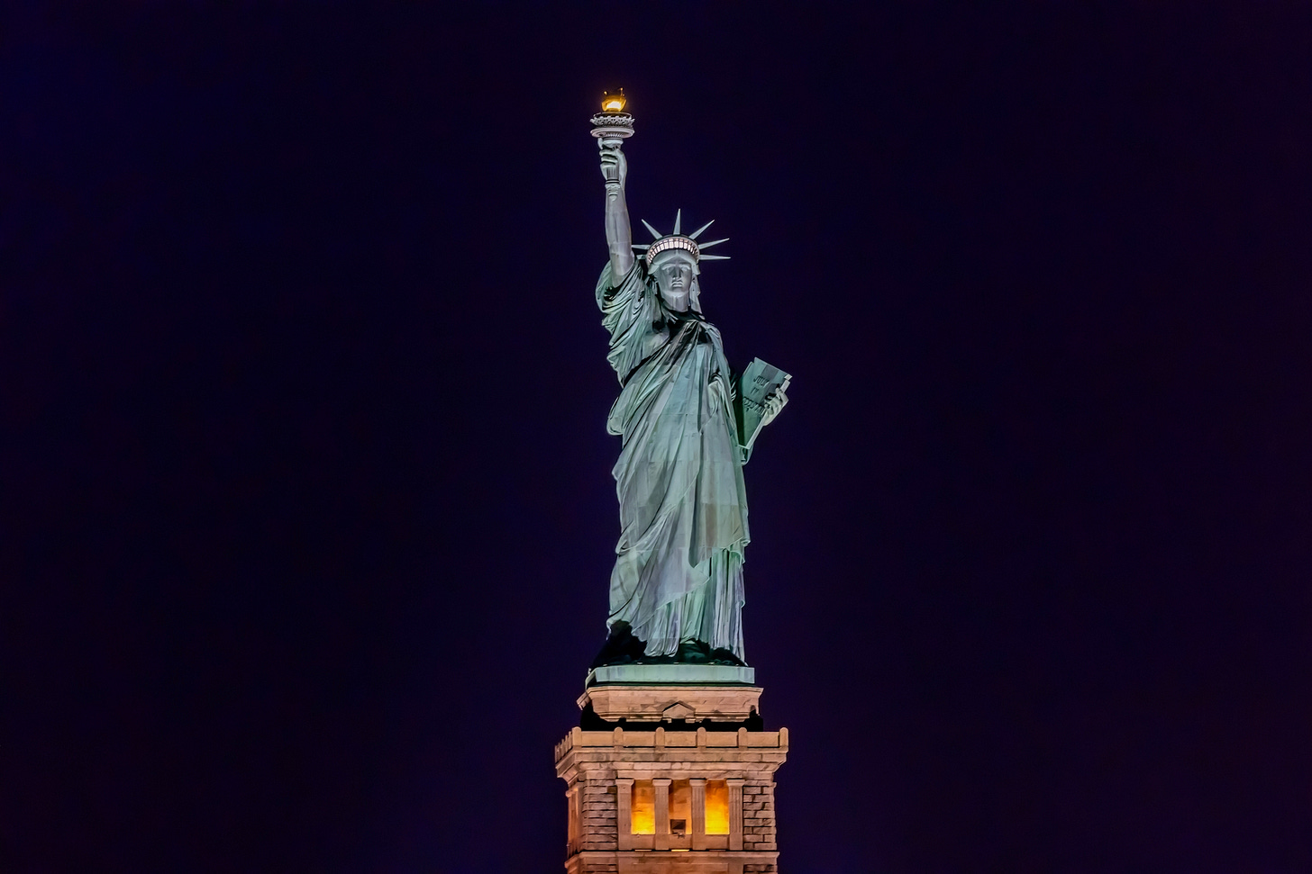 Nighttime photo of the Statue of Liberty against a dark sky