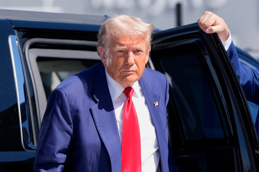 Former President Donald Trump in a suit and tie, arriving at Harry Reid International Airport to board a plane after a 2024 campaign trip in Las Vegas