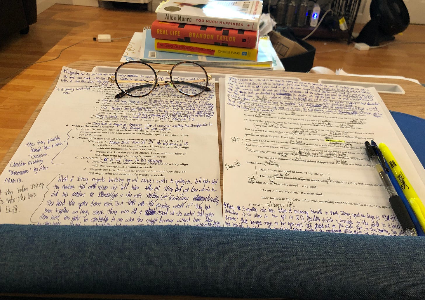 A photo of a lap desk holding print outs of Kat’s story, “Breathe for Them Both,” and its outline. Both documents are completely filled with messy line notes.