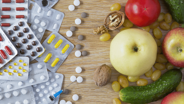 A table with pills and medicine on the left and fresh food on the right.
