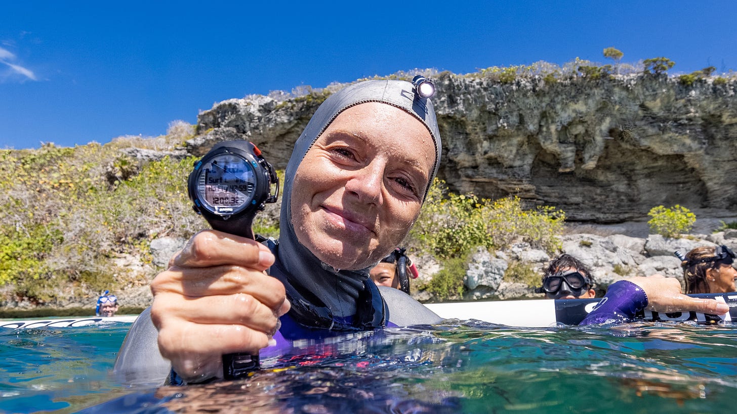 Freediver Alenka Artnik in the water holding a chronometer.