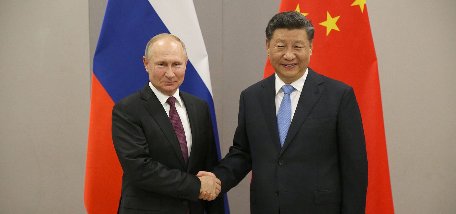 China's Xi Jinpeng and Russia's Vladimir Putin pose for a photo-op, shaking hands.