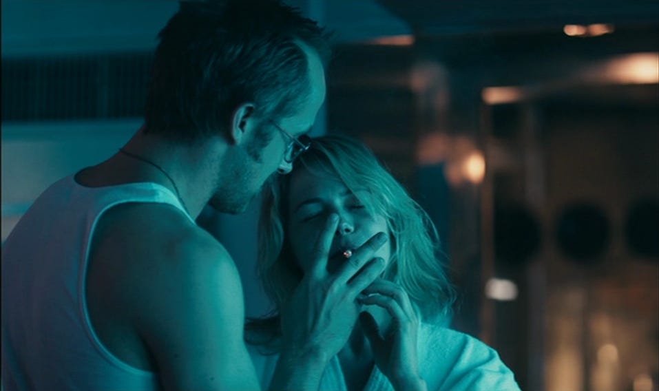 Movie still from Blue Valentine. A man holds up a cigarette for a woman, who smokes it.