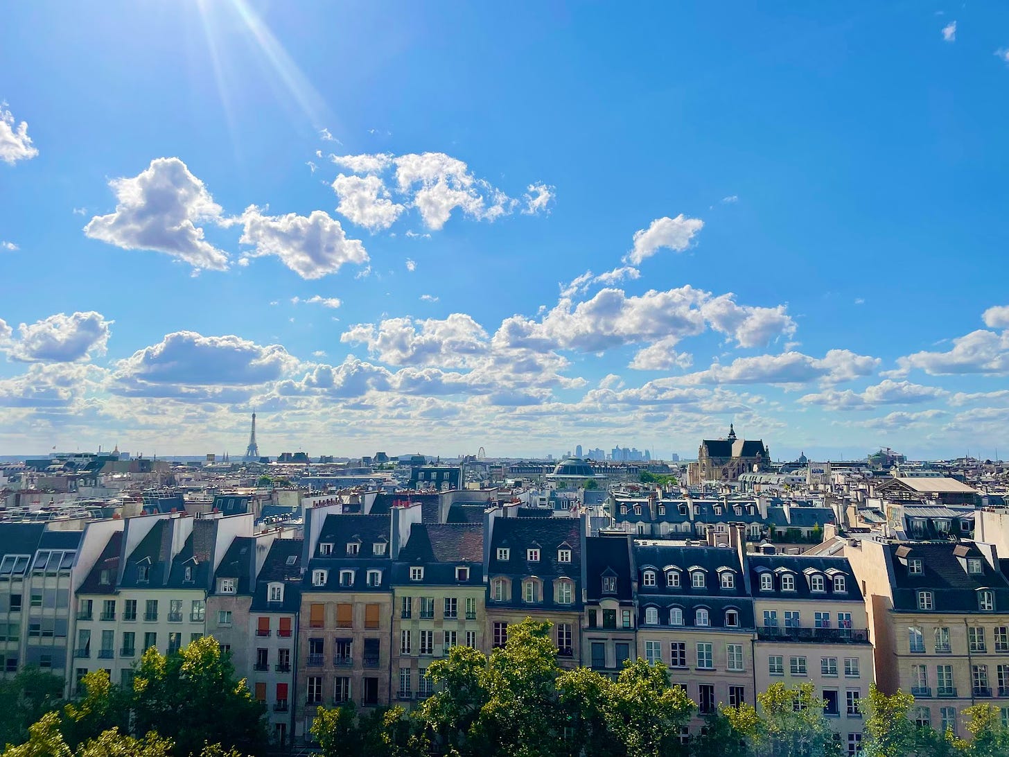 Paris, France, July 2022, a skyline of Paris with the Effiel Tower in the distant left hand corner with a blue sunny sky and city buildings in the foreground