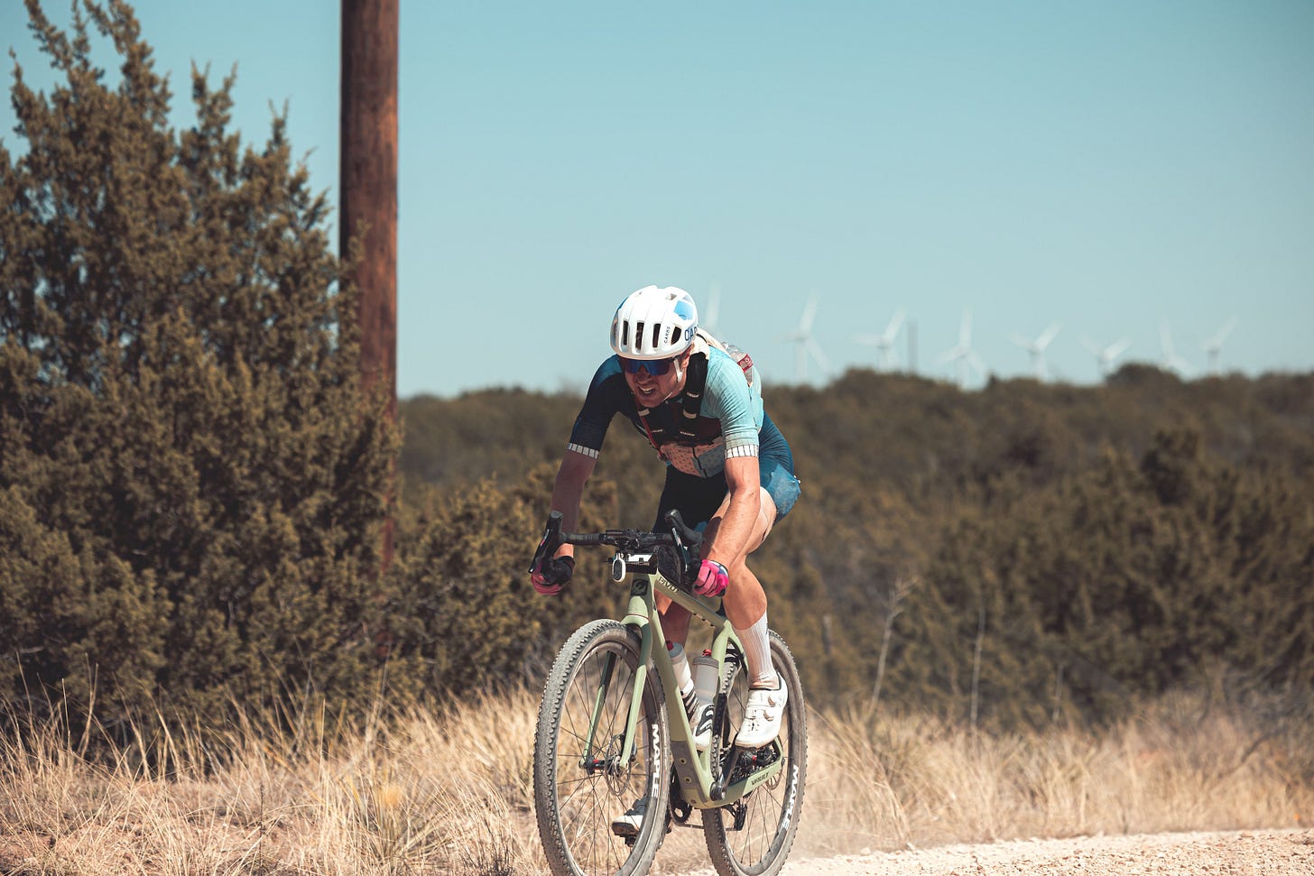 bike racer gritting his teeth in an all out chase during a gravel race