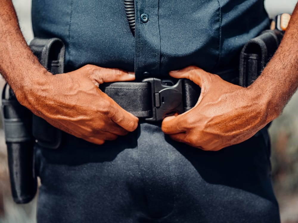 Free A Police Officer In Blue Uniform Holding a Black Belt Stock Photo