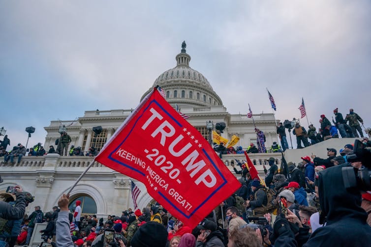 A Trump supporter waves a MAGA flag in front of the U.S. Capitol building. A Trump supporter waves a MAGA flag in front of the U.S. Capitol building.