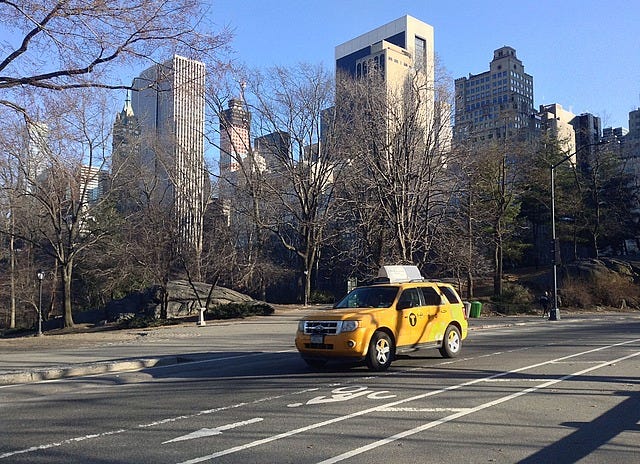 Yellow taxi in front of skyscrapers