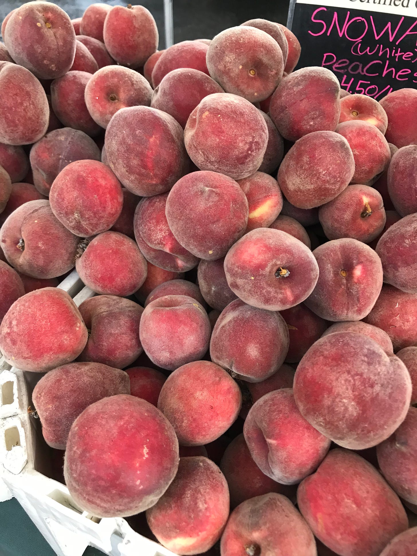 bin of peaches at a market stand