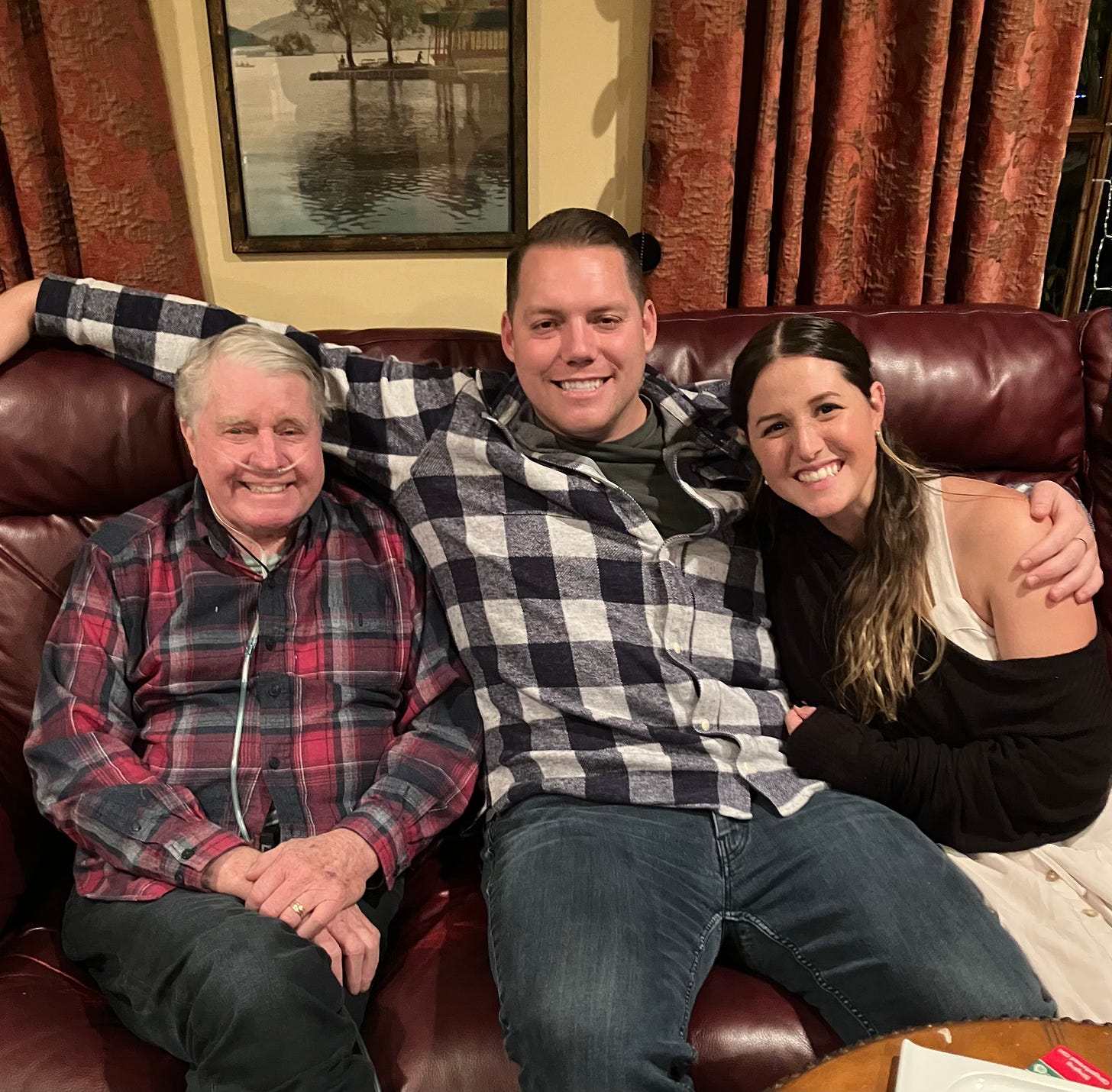 Grandfather sitting on couch with two adult grandkids
