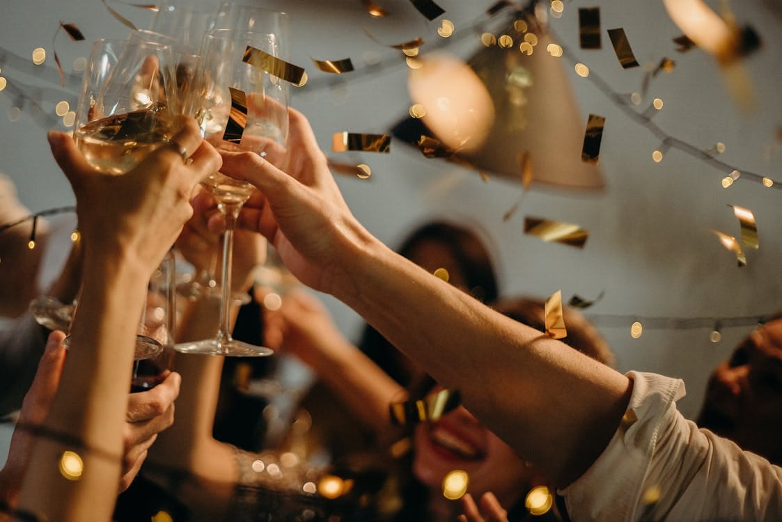 Free A lively indoor party scene with people toasting champagne glasses amid confetti and warm lights. Stock Photo