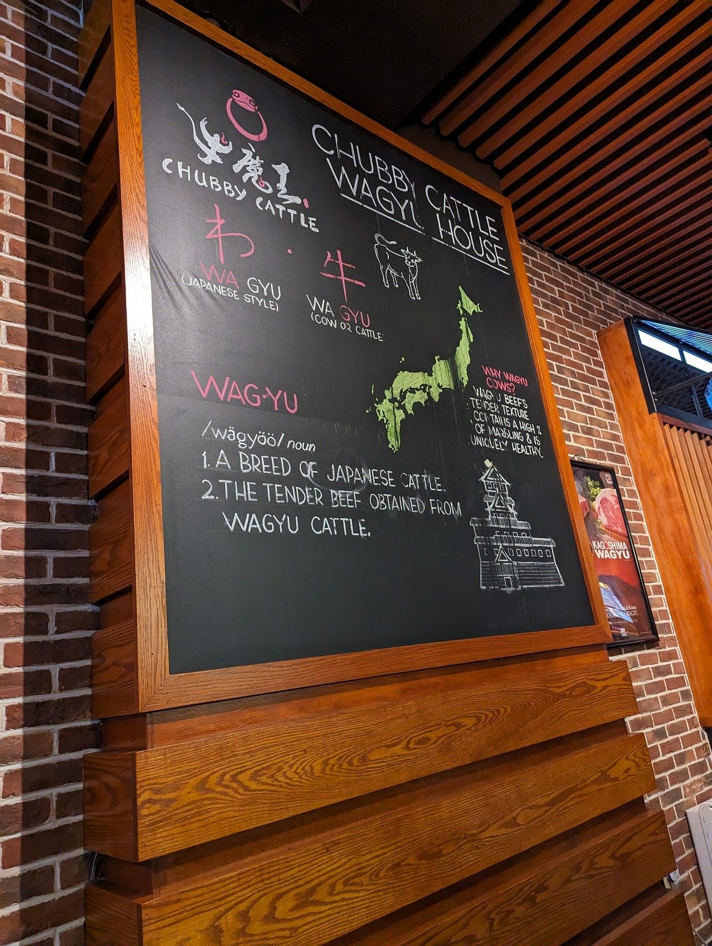 Chalkboard describing the Chubby Cattle and wagyu in general. There's a chair sketch of Japan, a cow, kanji, and the definition of wagyu.