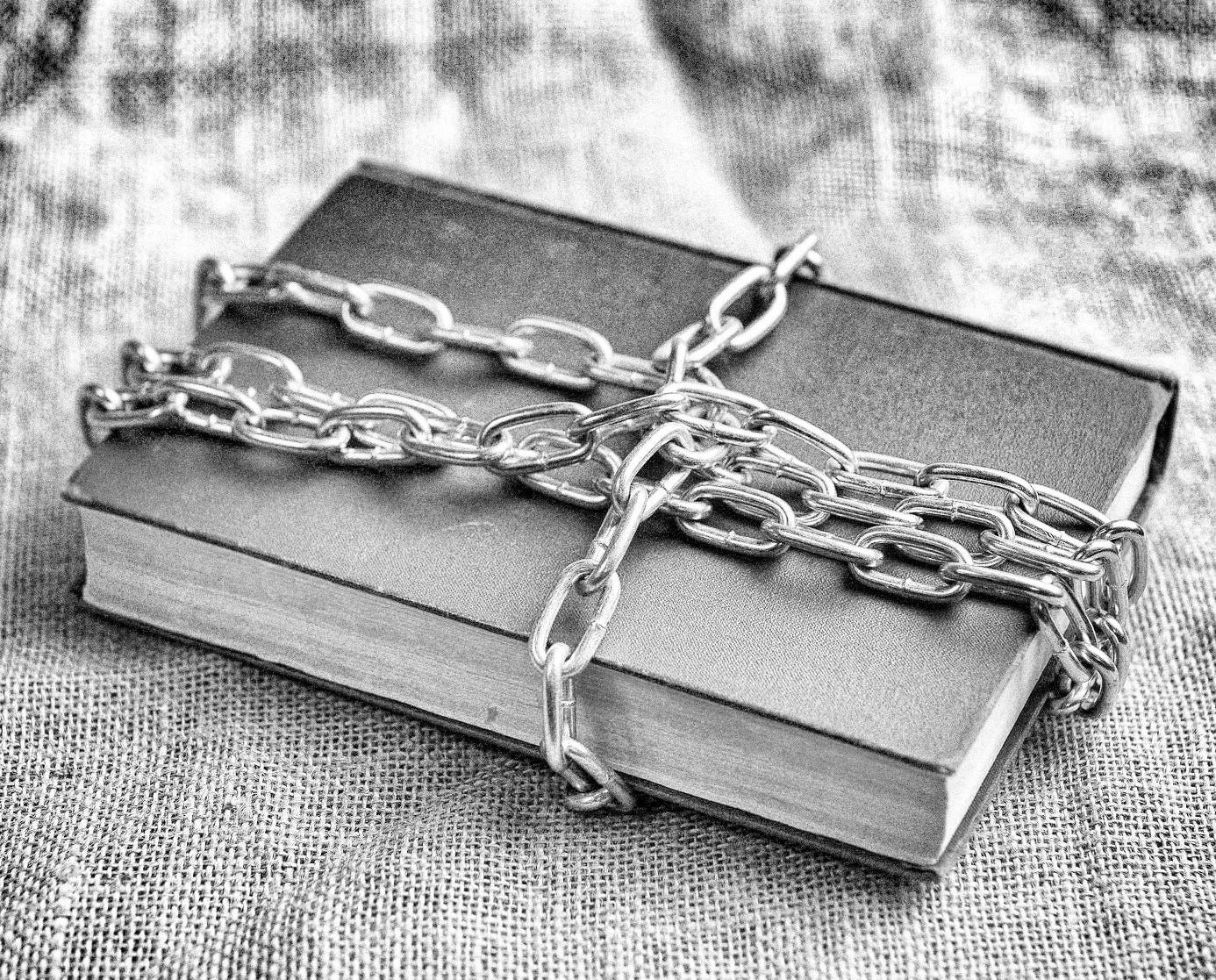 A black and white image of a book wrapped in chains.