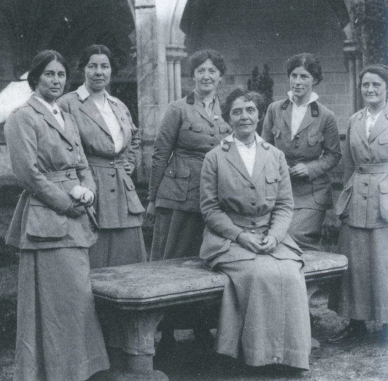 A black and white photograph from WWI with 6 Scottish ladies working in Roaumont's hospital, one is sitting on a bench, the others standing behind her: Frances Ivens (seated) and (standing, left to right) Dr. Agnes Savill, Ruth Nicholson, Dr. Jessie Augusta Berry, Dr. Winnifred Margaret Ross, and Dr M.D. Hancock.