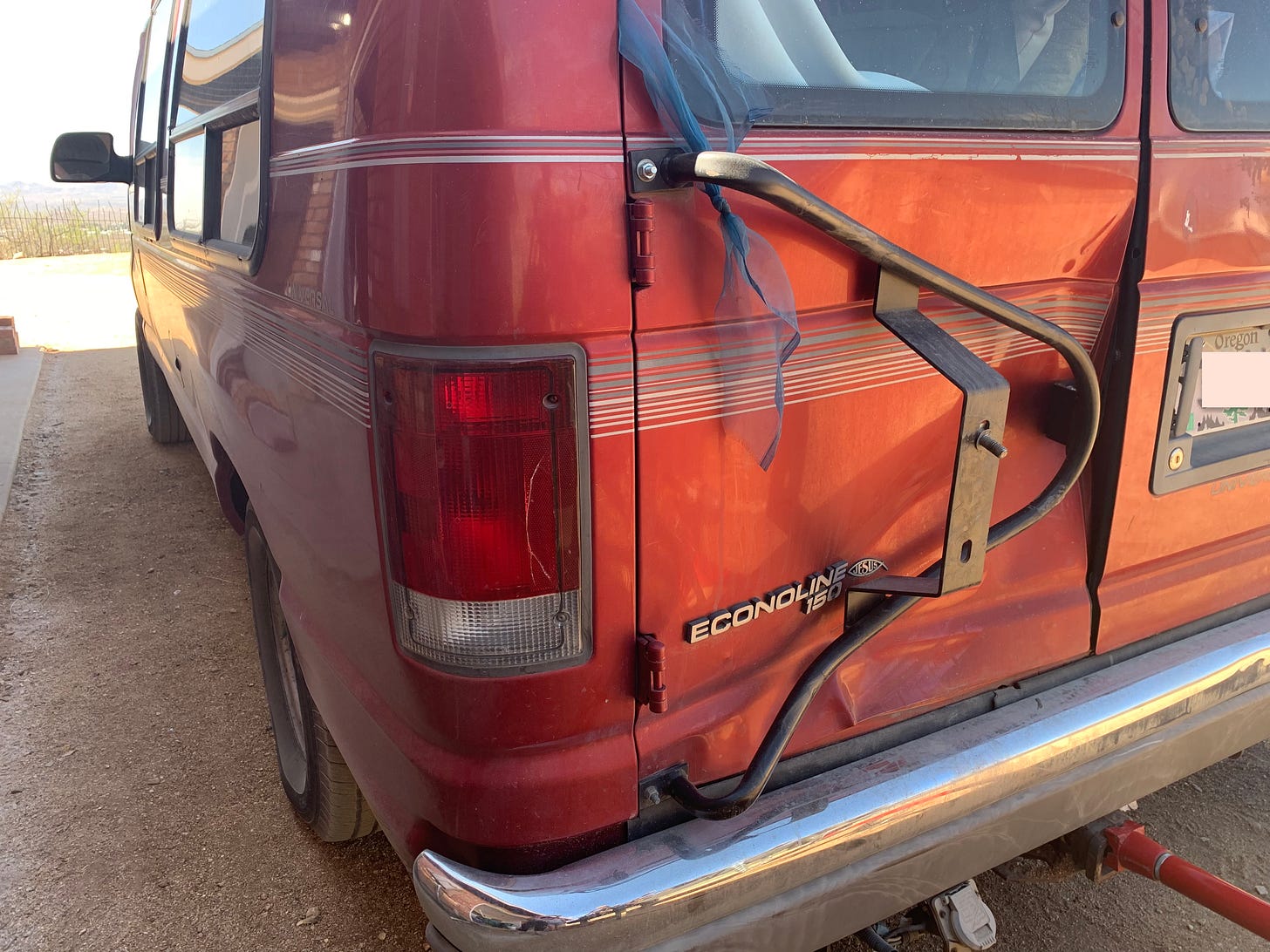 The back of the author's red Ford Econoline van, the passenger side of the door smashed in.