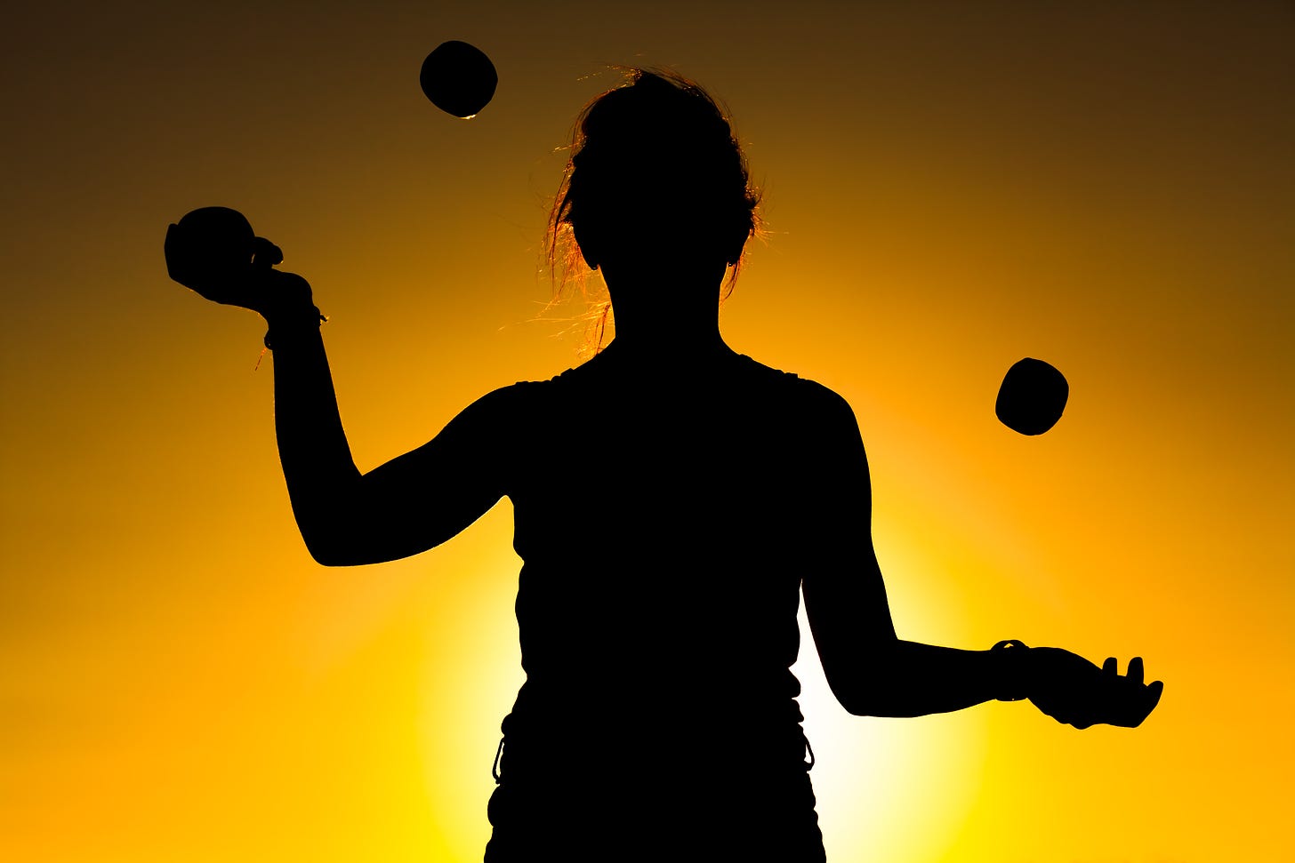 Adobe stock image of a woman juggling 3 balls in silhouette with the sun behind her