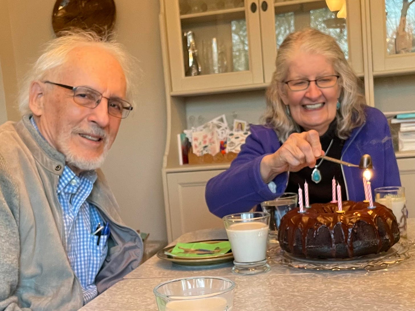 Mom snuffing out candles on her birthday cake, age 79, with Dad at her side