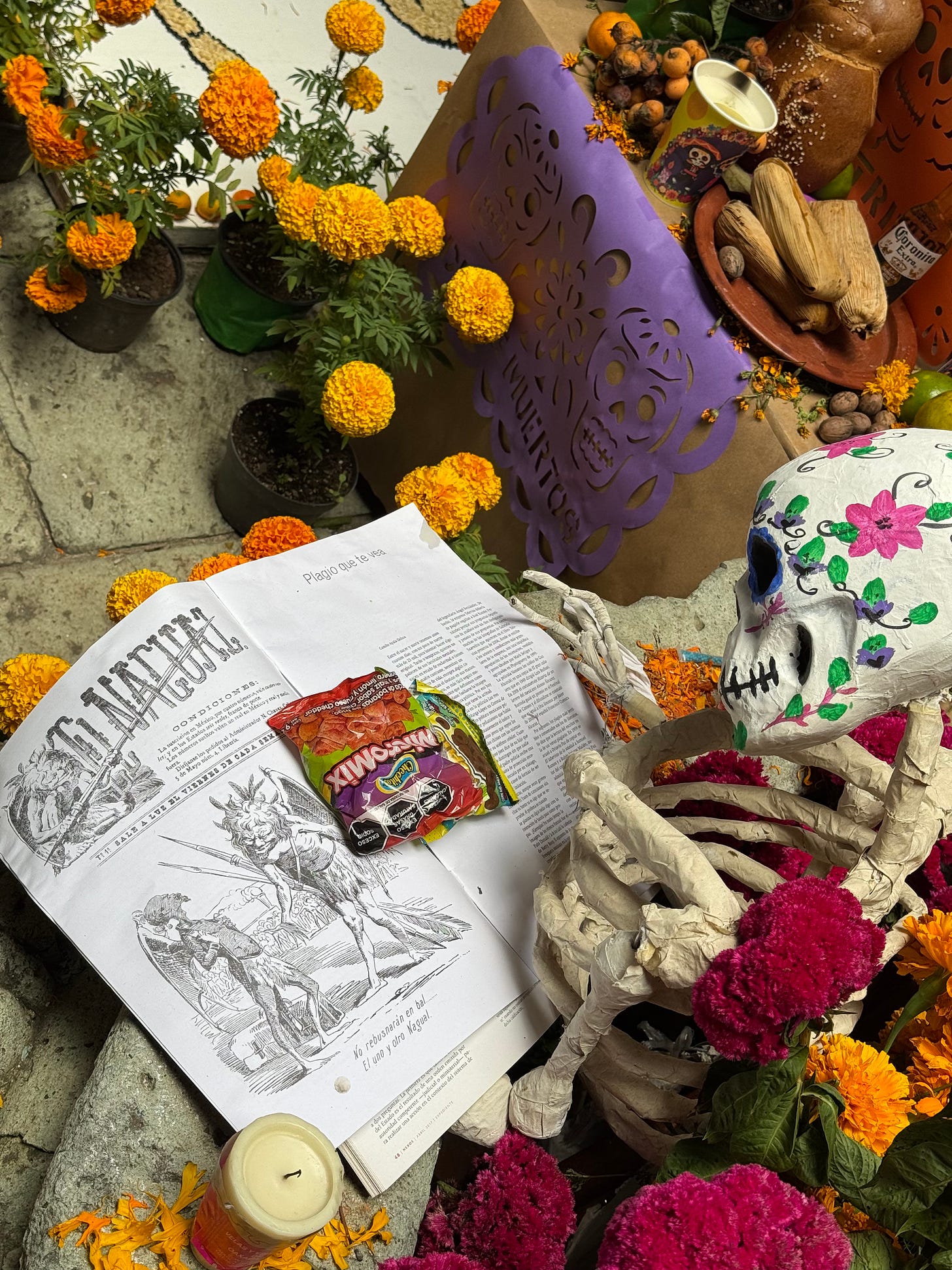 A paper mache skeleton reading a muertos-themed newspaper that is part of an ofrenda.