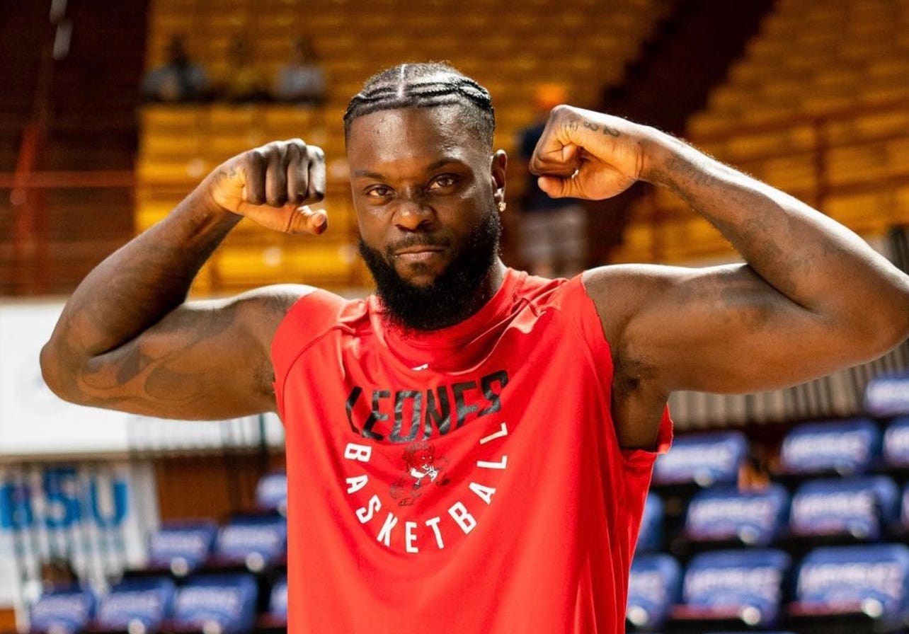 Lance Stephenson flexes for a camera in a cut-off Leones de Ponce red warmup shirt.