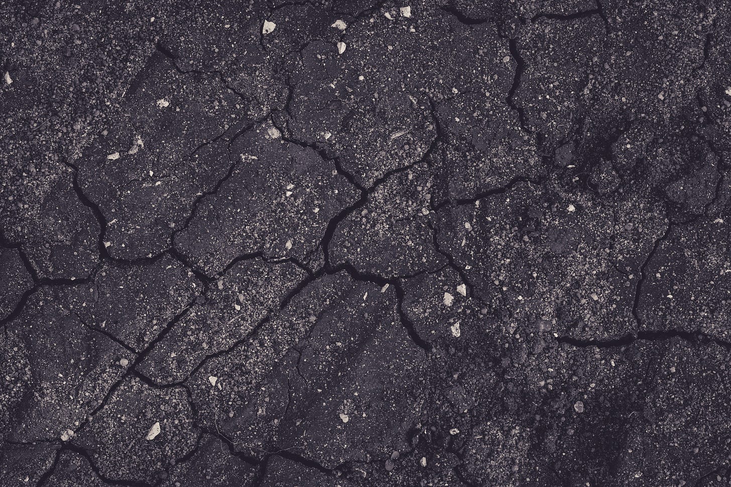 Dark pavement with cracks.