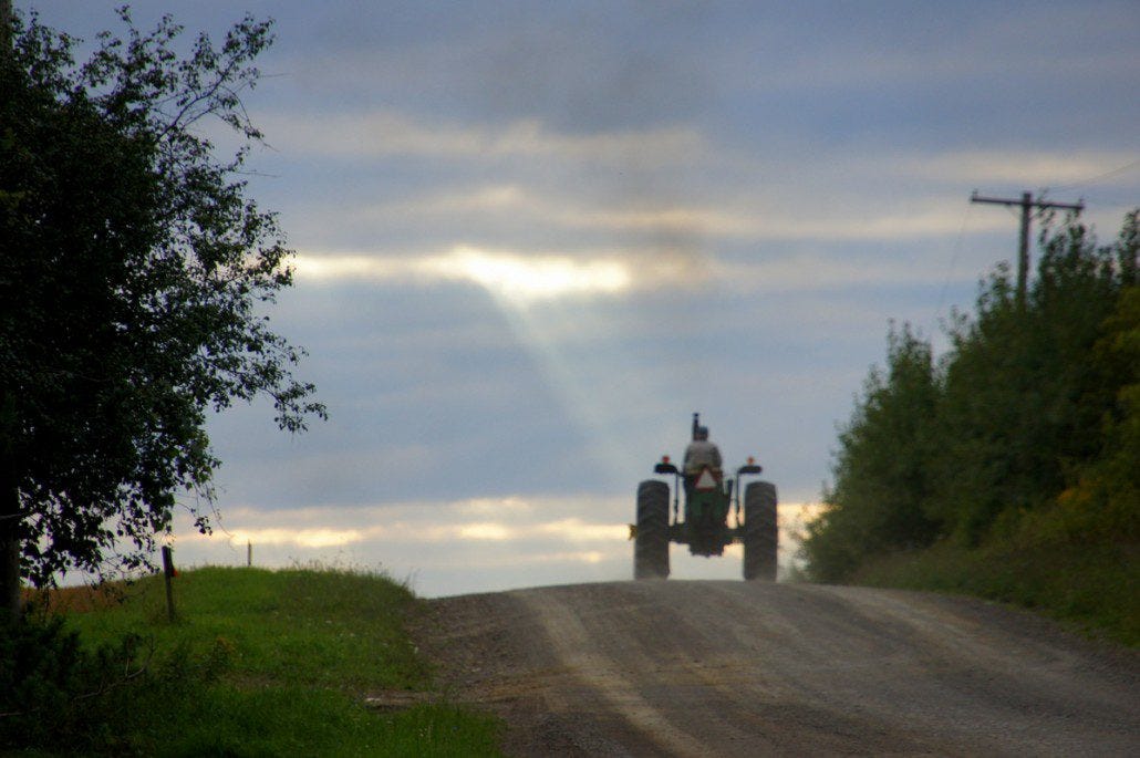 A farmer chugs off into the sunset after a day's work.