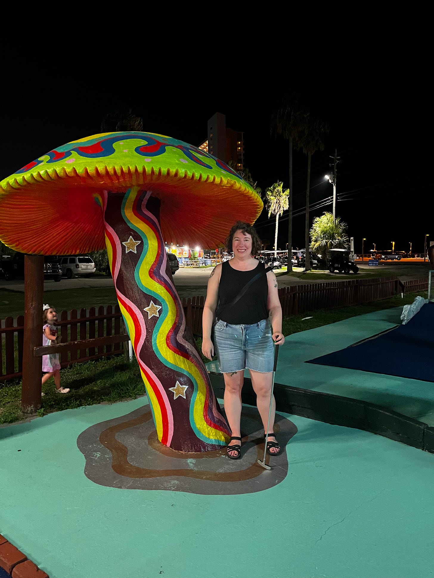 A photo of me on a miniature golf course, standing under a large concrete mushroom