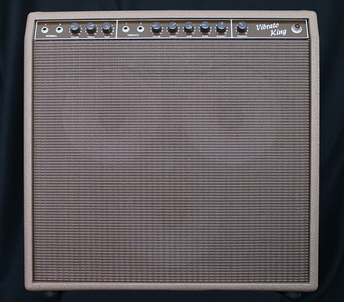 A brown Vibrato King guitar amp with knobs and mesh front