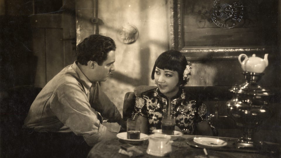 AMW and Fred Louis Lerch sit at a table talking in a scene from Pavement Butterfly (1929)