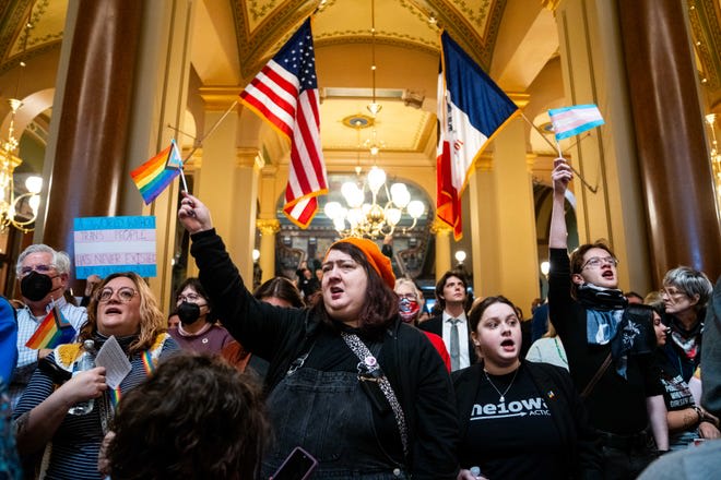 Jessica Bauer of Des Moines waves a pride flag as more than 1,000 protesters rally against legislation removing protections for trans people from the Iowa Civil Rights Act on Thursday, Feb. 27, 2025.