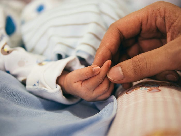 A mother touching her child’s hand.