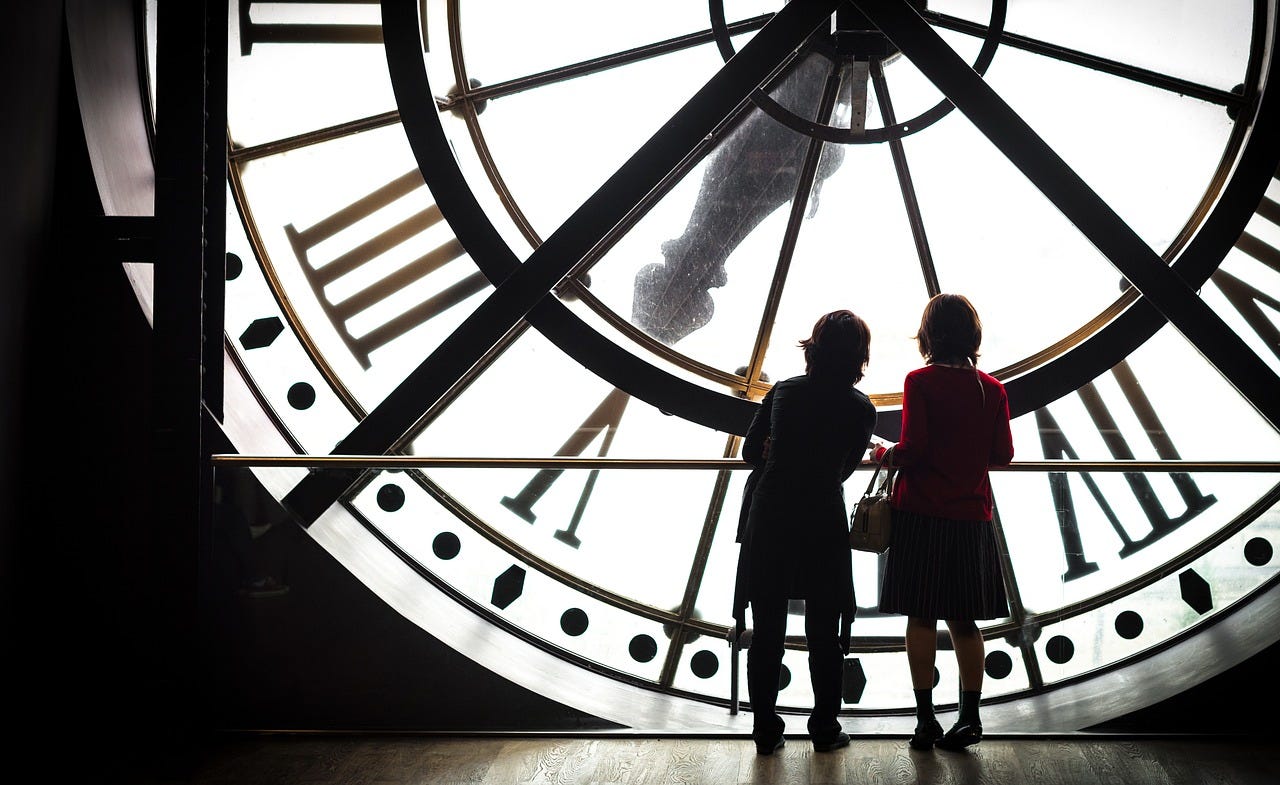 The silhouette of a large clockface with two women standing in front
